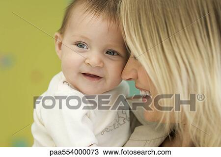 Stock Image - Mother holding baby next to face, close-up. Fotosearch