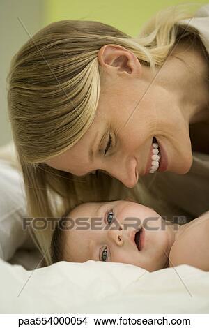 Picture - Mother leaning over baby, smiling. Fotosearch
