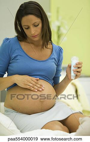 Pregnant woman applying moisturizer to belly View Large Photo Image Stock Photo - Pregnant woman applying moisturizer to belly. Fotosearch