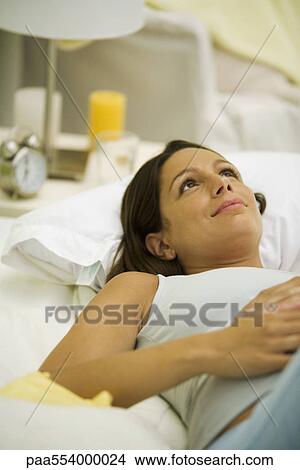 Picture - Pregnant woman lying on bed, daydreaming. Fotosearch