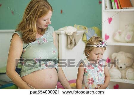 Stock Image - Pregnant woman playing with daughter. Fotosearch