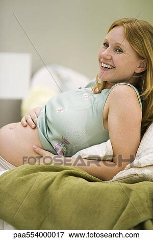 Pregnant woman reclining, hands on bare belly, smiling View Large Photo Image Stock Photo - Pregnant woman reclining, hands on bare belly, smiling. Fotosearch