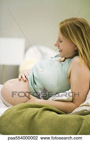 Pregnant woman relaxing, hand on belly View Large Photo Image Stock Image - Pregnant woman relaxing, hand on belly. Fotosearch