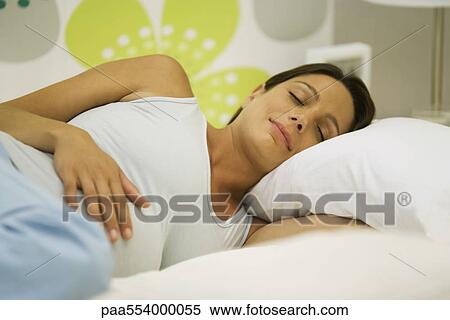 Stock Photography - Pregnant woman sleeping, hand on stomach. Fotosearch