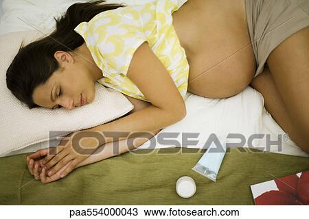 Stock Image - Tired pregnant woman lying on bed, resting. Fotosearch