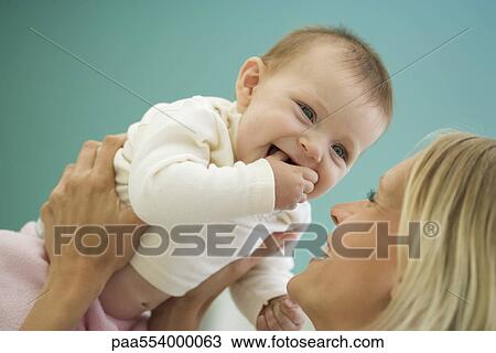 Stock Image - Woman picking up happy baby. Fotosearch