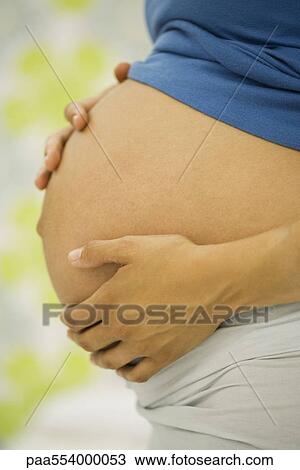 Stock Image - Woman's pregnant belly, side view. Fotosearch
