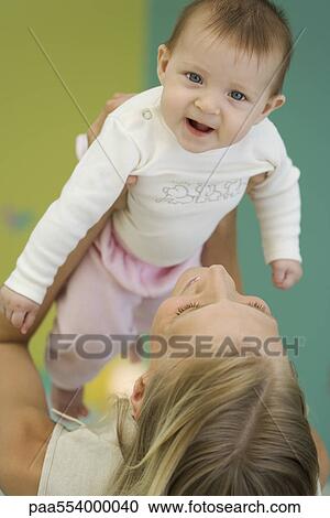 Young mother lifting up baby, baby smiling at camera View Large Photo Image Stock Image - Young mother lifting up baby, baby smiling at camera. Fotosearch