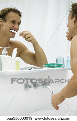 Man brushing teeth, looking at self in mirror View Large Photo Image Stock Photo - Man brushing teeth, looking at self in mirror. Fotosearch