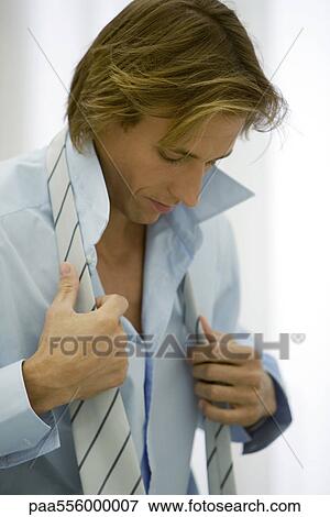 Stock Photo - Man getting dressed, putting on tie. Fotosearch