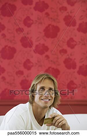 Man holding credit card, looking up and dreamily smiling View Large Photo Image Stock Photography - Man holding credit card, looking up and dreamily smiling. Fotosearch