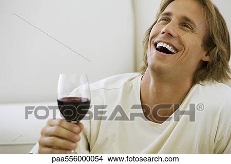 Man holding glass of red wine, laughing View Large Photo Image Picture - Man holding glass of red wine, laughing. Fotosearch