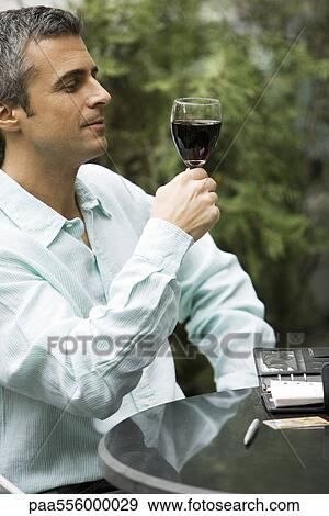 Man looking at glass of red wine View Large Photo Image Stock Photo - Man looking at glass of red wine. Fotosearch