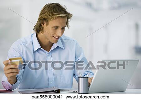 Stock Image - Man making online purchase with credit card. Fotosearch