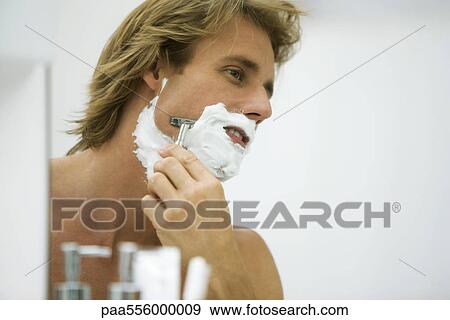 Man shaving with razor looking at self in mirror View Large Photo Image Stock Photo - Man shaving with razor looking at self in mirror. Fotosearch