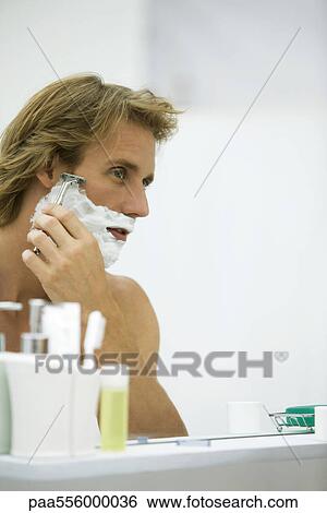 Man shaving with razor, looking at self in bathroom mirror View Large Photo Image Stock Photograph - Man shaving with razor, looking at self in bathroom mirror. Fotosearch