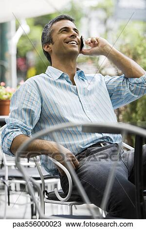Man sitting outdoors using cell phone View Large Photo Image Stock Image - Man sitting outdoors using cell phone. Fotosearch