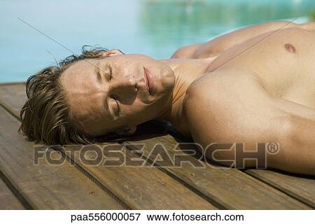 Man sunbathing at side of pool View Large Photo Image Stock Photo - Man sunbathing at side of pool. Fotosearch
