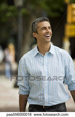 Man walking outdoors, smiling, looking away View Large Photo Image Stock Photo - Man walking outdoors, smiling, looking away. Fotosearch