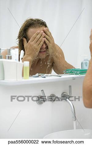 Man washing face in bathroom View Large Photo Image Stock Image - Man washing face in bathroom. Fotosearch