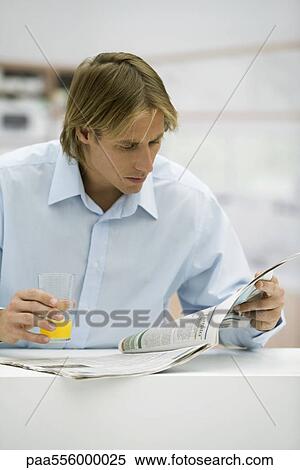 Man with glass of juice looking at newspaper View Large Photo Image Stock Photography - Man with glass of juice looking at newspaper. Fotosearch