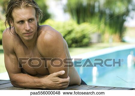 Stock Photo - Muscular swimmer resting at edge of pool, leaning on elbow looking away. Fotosearch