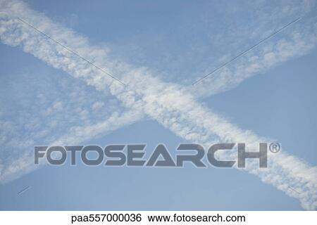 Stock Photograph - Vapor trails intersecting in blue sky. Fotosearch