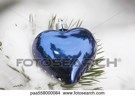 Heart shaped Christmas ornament on snow-covered evergreen branch View Large Photo Image Picture - Heart shaped Christmas ornament on snow-covered evergreen branch. Fotosearch