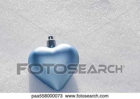 Stock Image - Heart shaped ornament lying on snow. Fotosearch