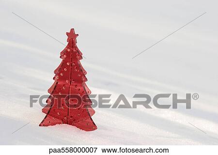 Stock Photo - Red plastic Christmas tree decoration set in snow. Fotosearch