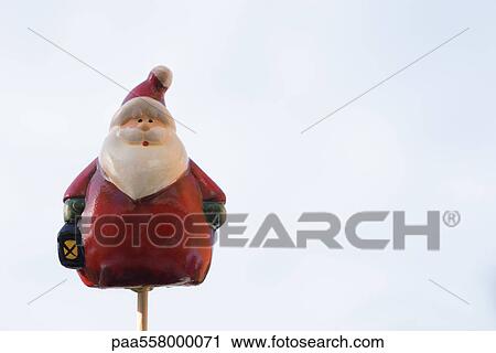 Stock Image - Santa Claus figurine on thin wooden post. Fotosearch