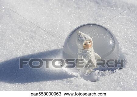 Snow globe in snow, figurine of little girl wearing winter coat and hat looking out View Large Photo Image Stock Image - Snow globe in snow, figurine of little girl wearing winter coat and hat looking out. Fotosearch