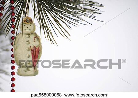 Snowman Christmas ornament and beaded garland hanging from snow-covered tree branch View Large Photo Image Stock Photo - Snowman Christmas ornament and beaded garland hanging from snow-covered tree branch. Fotosearch