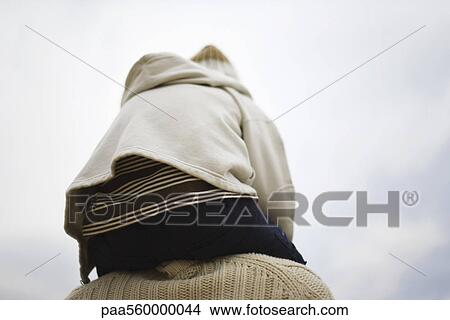 Child sitting on parent's shoulders, rear view View Large Photo Image Picture - Child sitting on parent's shoulders, rear view. Fotosearch