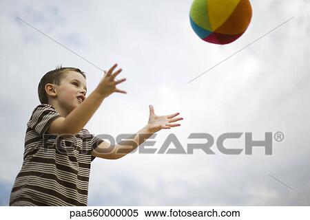 Stock Photography - Little boy catching ball, low angle view. Fotosearch