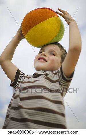 Little boy holding ball on top of head View Large Photo Image Stock Image - Little boy holding ball on top of head. Fotosearch