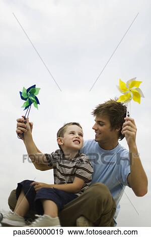 Little boy sitting on father's lap, both holding pinwheels View Large Photo Image Stock Photo - Little boy sitting on father's lap, both holding pinwheels. Fotosearch