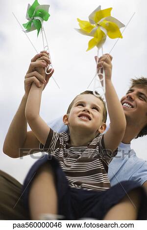 Little boy sitting on father's lap, both holding pinwheels View Large Photo Image Stock Photograph - Little boy sitting on father's lap, both holding pinwheels. Fotosearch