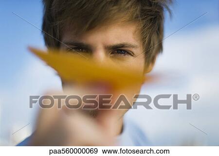 Young man aiming paper airplane at camera View Large Photo Image Stock Photo - Young man aiming paper airplane at camera. Fotosearch