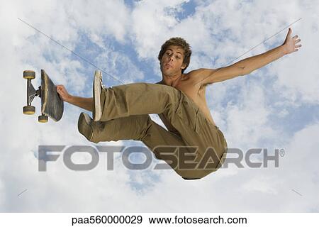 Young man jumping midair with skateboard View Large Photo Image Stock Photo - Young man jumping midair with skateboard. Fotosearch