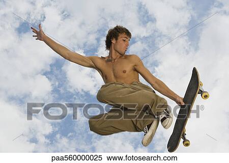 Young man jumping midair with skateboard View Large Photo Image Stock Photography - Young man jumping midair with skateboard. Fotosearch
