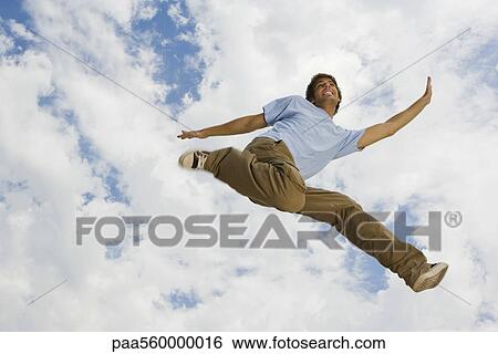 Young man leaping joyfully in midair, low angle view View Large Photo Image Stock Photograph - Young man leaping joyfully in midair, low angle view. Fotosearch