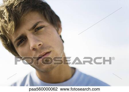 Young man looking at camera with head tilted and brow furrowed View Large Photo Image Stock Image - Young man looking at camera with head tilted and brow furrowed. Fotosearch