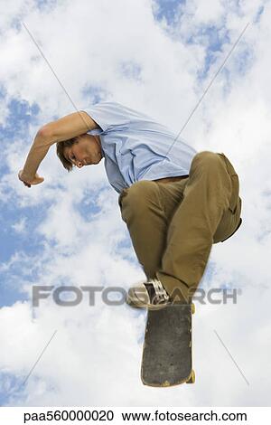 Young man performing skateboarding trick in midair View Large Photo Image Stock Image - Young man performing skateboarding trick in midair. Fotosearch