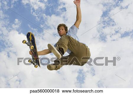 Stock Photo - Young man performing skateboarding trick in midair. Fotosearch