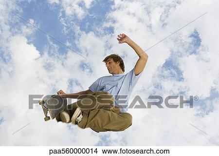 Young man with skateboard in midair View Large Photo Image Picture - Young man with skateboard in midair. Fotosearch