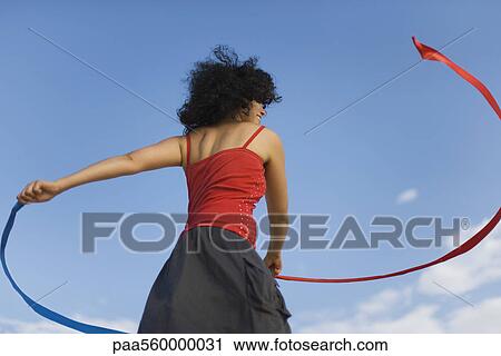 Young woman spinning around with ribbons outdoors View Large Photo Image Stock Image - Young woman spinning around with ribbons outdoors. Fotosearch