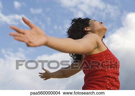 Young woman standing outdoors with arms out, head back View Large Photo Image Picture - Young woman standing outdoors with arms out, head back. Fotosearch