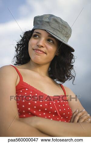 Young woman wearing cap turned to side, arms folded, portrait View Large Photo Image Stock Photo - Young woman wearing cap turned to side, arms folded, portrait. Fotosearch