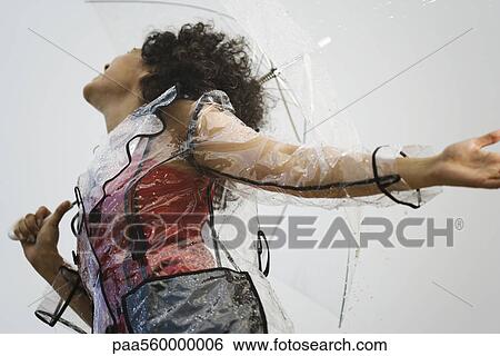 Young woman wearing clear plastic raincoat standing in rain, low angle view View Large Photo Image Stock Photograph - Young woman wearing clear plastic raincoat standing in rain, low angle view. Fotosearch